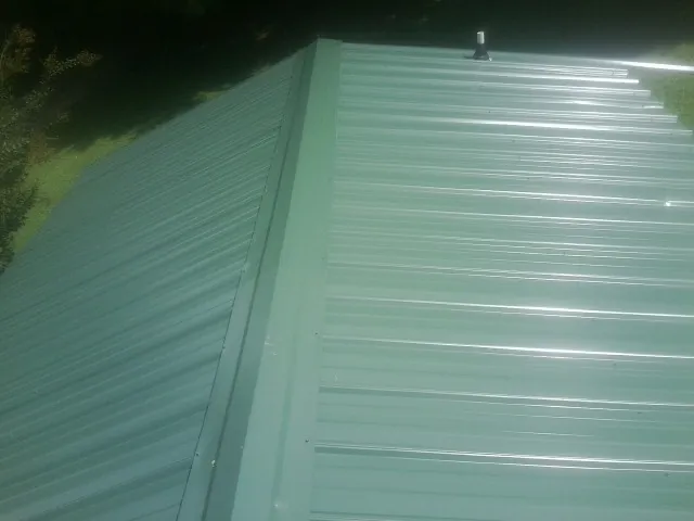 New green metal panels meeting at the ridge of a roof — Flat Roof Repair work by our crew in Viola