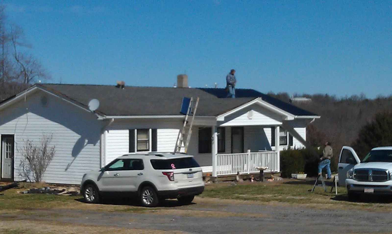 Roofers stripping shingles from a white ranch house roof in Viola